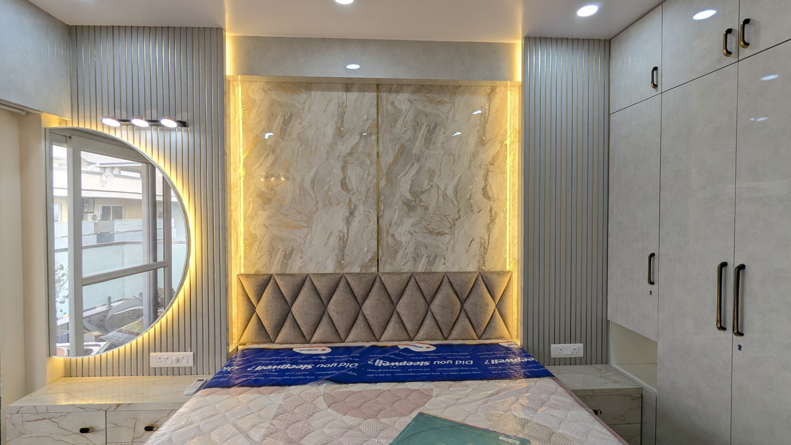 Luxury master bedroom interior with headboard, false ceiling and warm lighting designed by Interior Bee in Patna.
