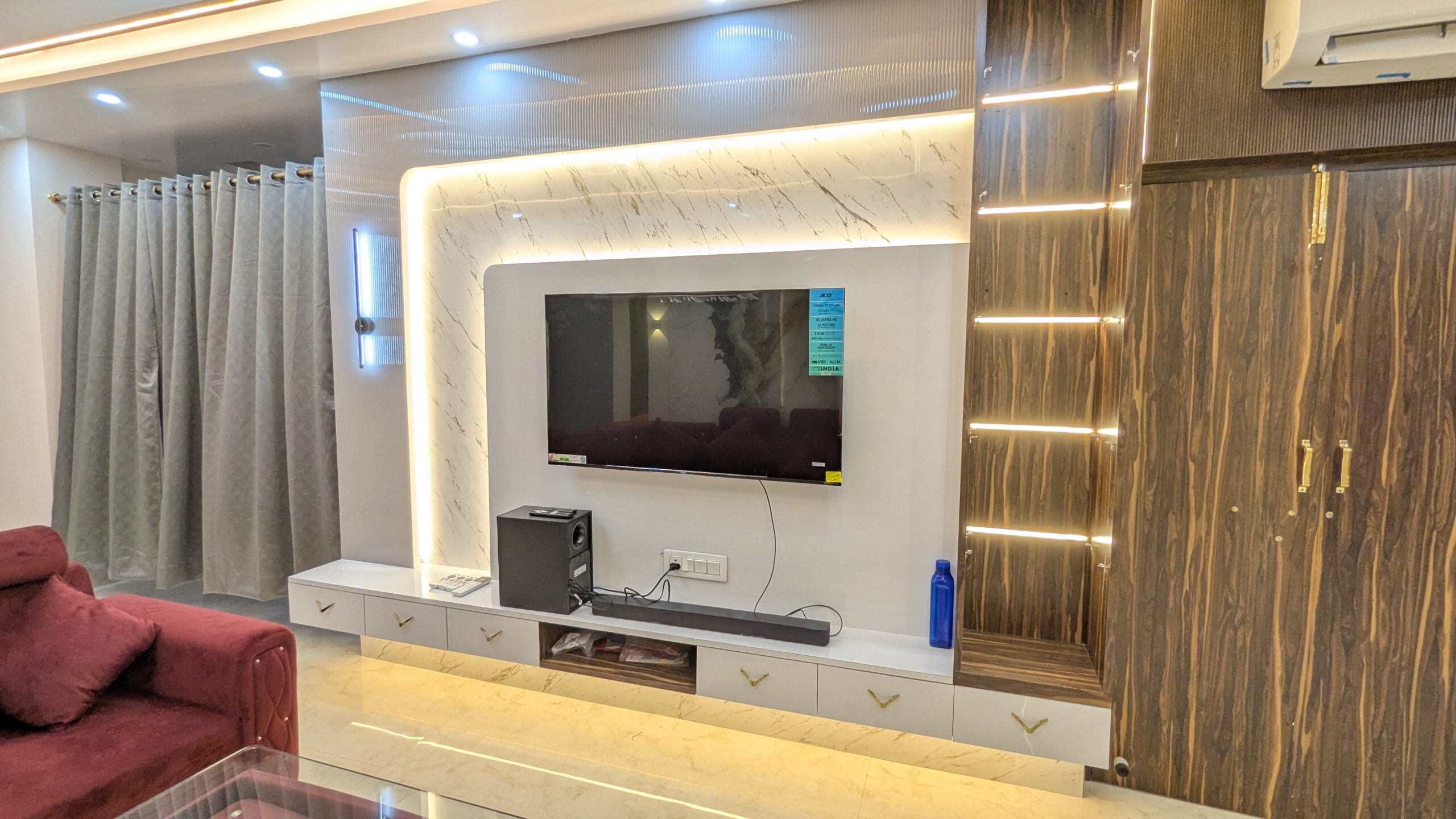 Modern living room interior with TV unit, decorative wall panel and ambient lighting by Interior Bee in Patna.